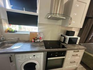 a small kitchen with a sink and a microwave at Wimbledon Family Studio Flat 1 in London