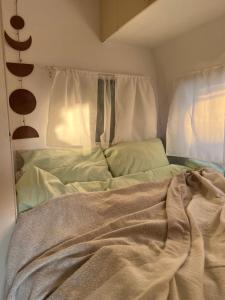 an unmade bed with a blanket in a bedroom at Przyczepa Kempingowa Beige in Jastarnia