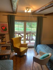 a living room with a bed and a chair and a window at Willa Plejady in Karpacz
