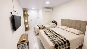 a hotel room with two beds and a tv at Suíte próximo a BR! in São José