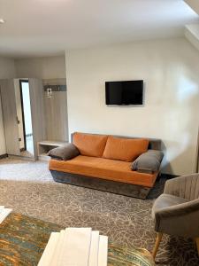 an orange couch in a living room with a tv at Pensiunea Luceafărul Sibiu in Sibiu +26 photos
