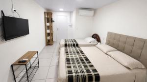 a room with two beds and a flat screen tv at Suíte próximo a BR! in São José