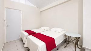 a white bedroom with two beds and a stool at Suíte próximo a BR! in São José