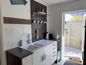 a white kitchen with a sink and a shower at Texelheerlijk 1 in De Koog