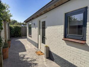 a white brick house with a window and a sidewalk at Texelheerlijk 1 in De Koog