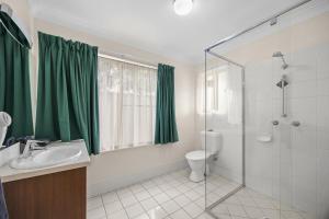 a bathroom with a green shower curtain and a toilet at Maynestay Motel in Gunnedah +16 photos