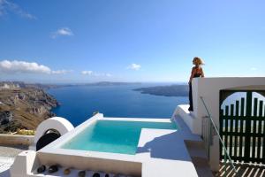 a woman standing on the side of a house with a swimming pool at Villa Murat in Fira