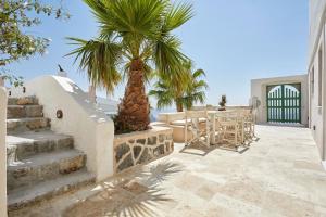 a patio with a palm tree and a table and chairs at Villa Murat in Fira