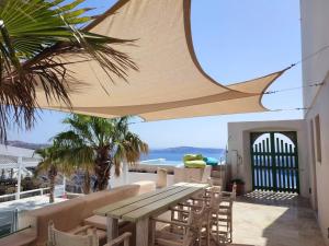 a patio with a wooden table and chairs under an umbrella at Villa Murat in Fira +44 photos