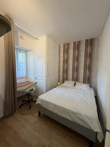 a bedroom with a bed and a desk and a window at Meublé paisible in Tonnerre