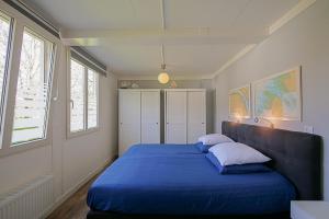 a bedroom with a blue bed with two pillows at Vakantiehuis Zeevogel - Julianadorp aan Zee in Julianadorp