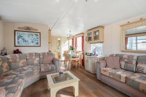 a living room with couches and a table at Chalet Huffels P12 - Camping De Nollen Callantsoog in Callantsoog