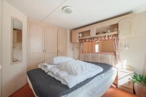a bedroom with a bed with white sheets and a window at Chalet Huffels P12 - Camping De Nollen Callantsoog in Callantsoog