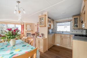 a kitchen with wooden cabinets and a table with a vase of flowers at Chalet Huffels P12 - Camping De Nollen Callantsoog in Callantsoog +36 photos