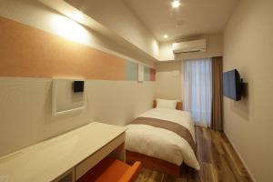 a bedroom with a bed and a desk and a television at SARASA HOTEL Shinsaibashi in Osaka