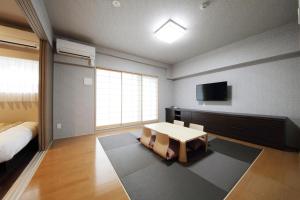 a bedroom with a bed and a table and a tv at SARASA HOTEL Shinsaibashi in Osaka