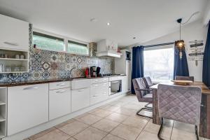 a kitchen with white cabinets and a table with chairs at Vakantiehuis Beau - Julianadorp aan Zee in Julianadorp