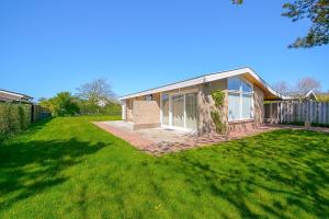 a house with a grass yard in front of it at Vakantiehuis Duynloper - Julianadorp aan Zee in Julianadorp