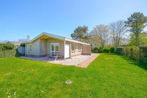 a small house in a yard with a green lawn at Vakantiehuis Duynloper - Julianadorp aan Zee in Julianadorp