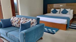a bedroom with a bed and a blue couch at Le Ranch Hôtel San-Pedro in San-Pédro