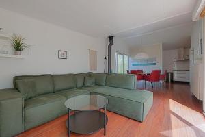 a living room with a green couch and a table at Vakantiehuis Springtij met privé zwembad - Julianadorp aan Zee in Julianadorp