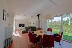 a dining room and living room with a table and chairs at Vakantiehuis Springtij met privé zwembad - Julianadorp aan Zee in Julianadorp