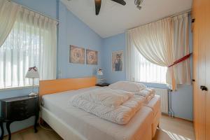 a bed in a bedroom with blue walls and windows at Vakantiehuis Springtij met privé zwembad - Julianadorp aan Zee in Julianadorp