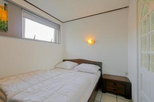 a white bedroom with a bed and a window at Tiny House Petite - Callantsoog aan Zee in Callantsoog