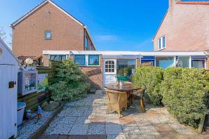 a patio with a wooden table in a yard at Tiny House Petite - Callantsoog aan Zee in Callantsoog