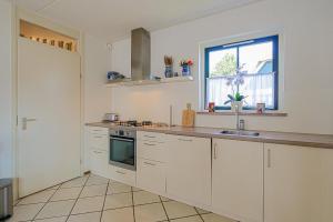 a kitchen with white cabinets and a sink and a window at Villa Schaut - Villapark De Buitenplaats Callantsoog aan Zee in Callantsoog