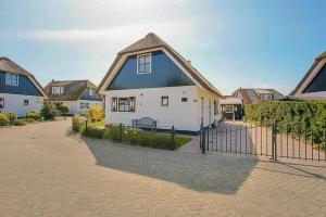 a white house with a black roof and a fence at Villa Schaut - Villapark De Buitenplaats Callantsoog aan Zee in Callantsoog