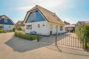 a white house with a blue roof behind a fence at Villa Schaut - Villapark De Buitenplaats Callantsoog aan Zee in Callantsoog +69 photos