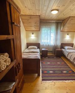 a bedroom with two beds and a rug at Chalet Rovenka in Verkhovyna