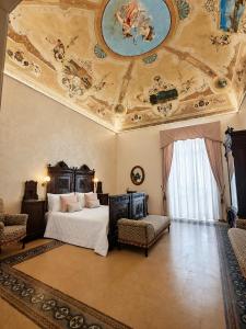 a bedroom with a bed and a ceiling with paintings at Palazzo Il Cavaliere B&B De Charme in Modica