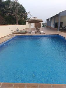 a large blue swimming pool with chairs and an umbrella at Casa Erica in Soyo