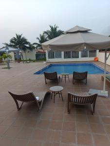 a pool with benches and an umbrella and a table and chairs at Casa Erica in Soyo