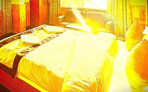a bedroom with a large bed with a yellow bedspread at The Trisha Hotel in kolkata