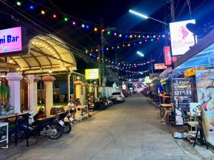 an empty street with people sitting at tables and lights at Kat's GuestHouse in Hua Hin