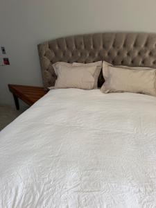 a large bed with white sheets and pillows at Highveld Nook in Sasolburg