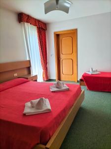 a bedroom with a red bed with two towels on it at Hotel Vael in Vigo di Fassa