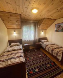 two beds in a room with wooden ceilings at Chalet Rovenka in Verkhovyna