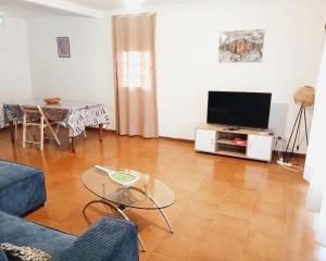a living room with a television and a table at Villa creole in Le Diamant