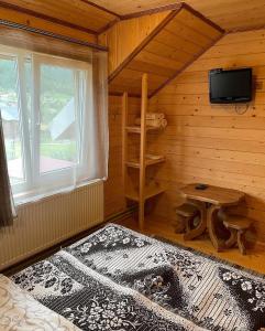 a bedroom with a bed and a tv in a cabin at Chalet Rovenka in Verkhovyna