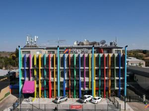 a colorful building with cars parked in front of it at Next To Apartment Hotel in Pretoria