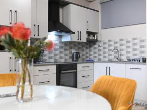 a kitchen with a table with a vase of flowers on it at Next To Apartment Hotel in Pretoria