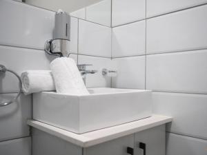 a white bathroom with a sink and a mirror at Next To Apartment Hotel in Pretoria +31 photos