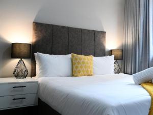 a bedroom with two beds and two lamps at Next To Apartment Hotel in Pretoria