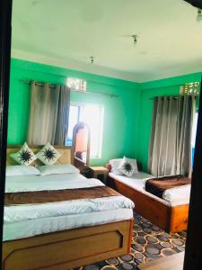 a bedroom with two beds and a green wall at Gauri Shanker Hotel and Lodge in Dharān Bāzār