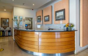 eine große Holzbar in einer Lobby mit Blumen in der Unterkunft Paliria Hotel in Chalkida