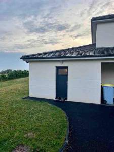 a white house with a black door and a yard at Studio paisible, 30m2 in La Souterraine +1 photo